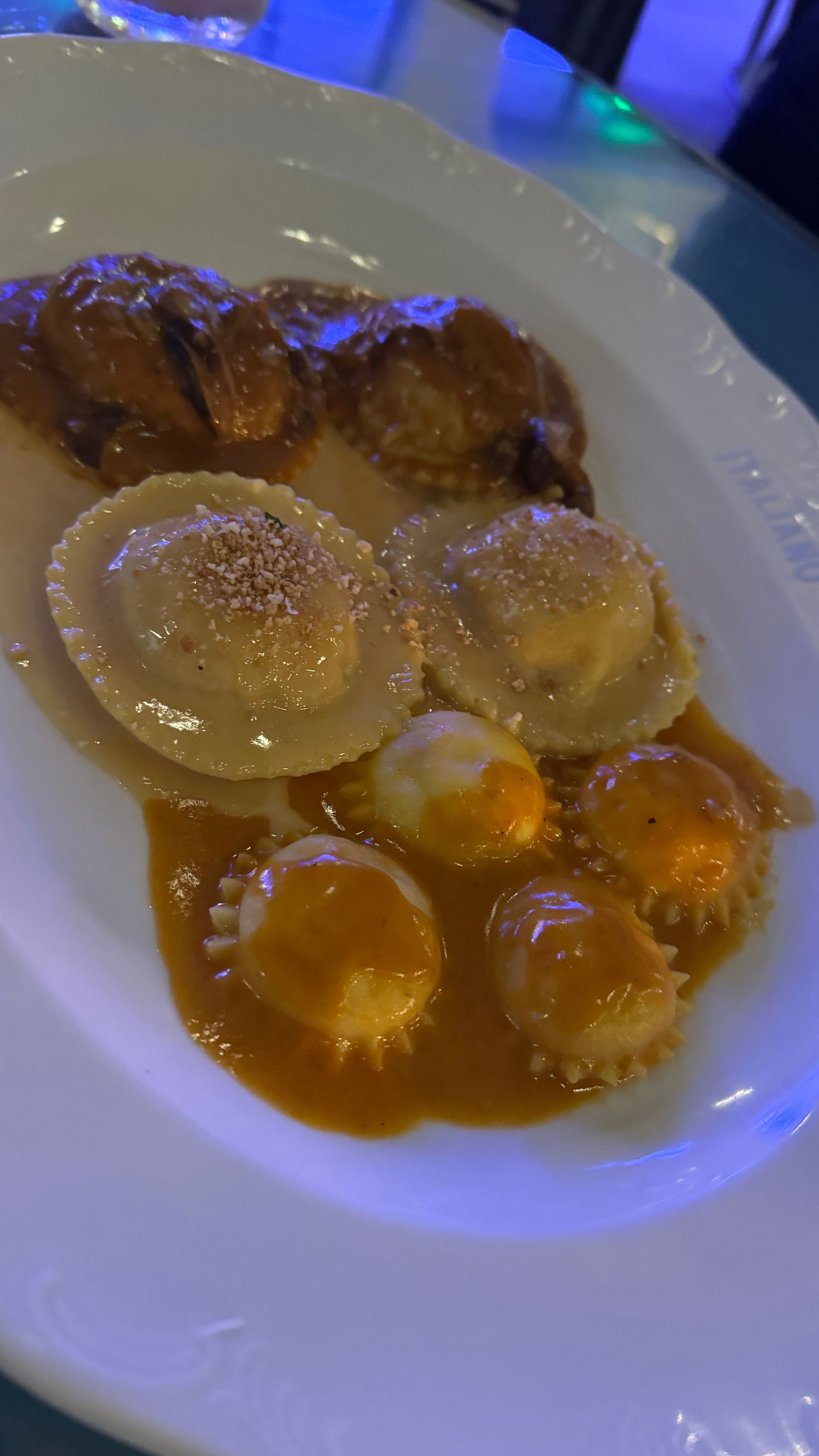 A close up of a plate of food with ravioli and meatballs on a table.