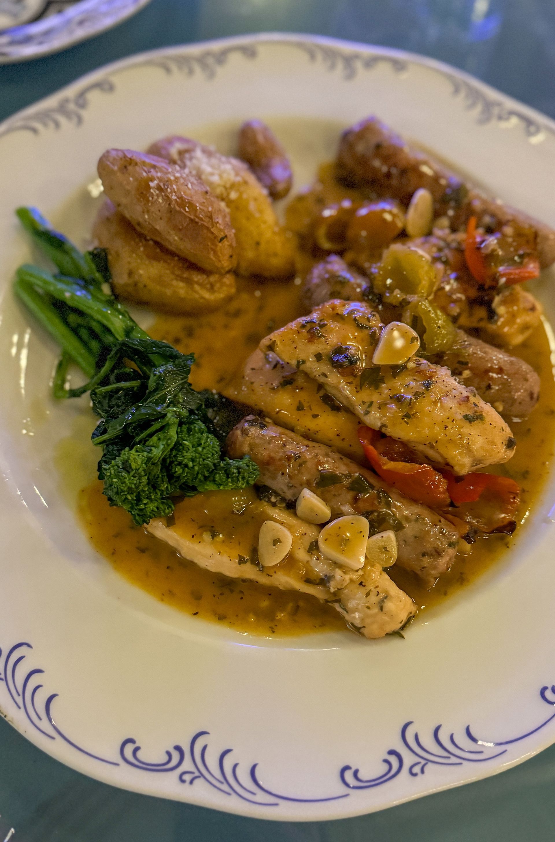 A white plate topped with chicken , sausage , broccoli and potatoes.