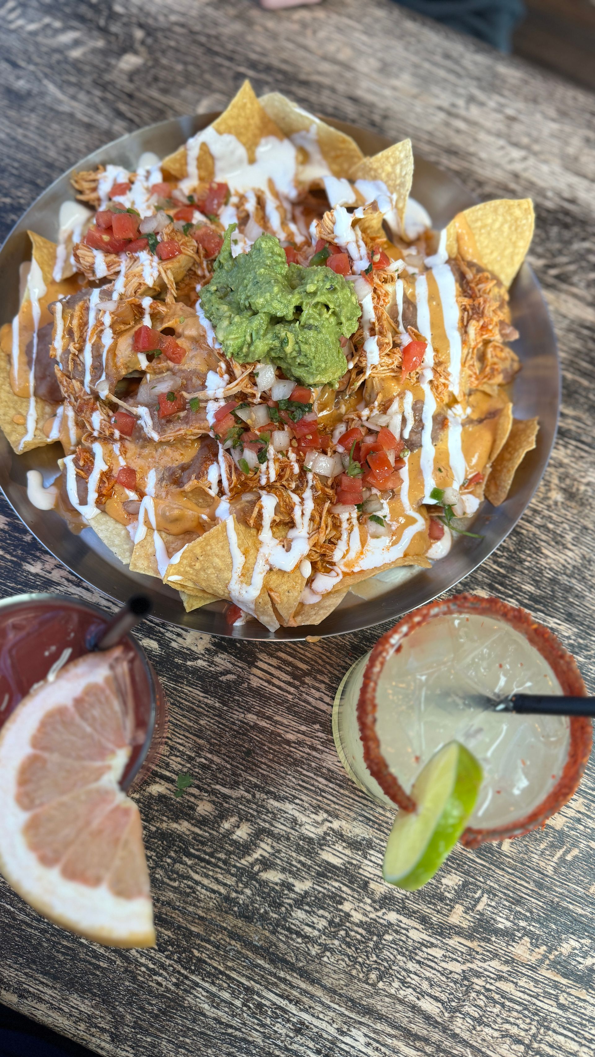 A plate of nachos and a drink on a table.