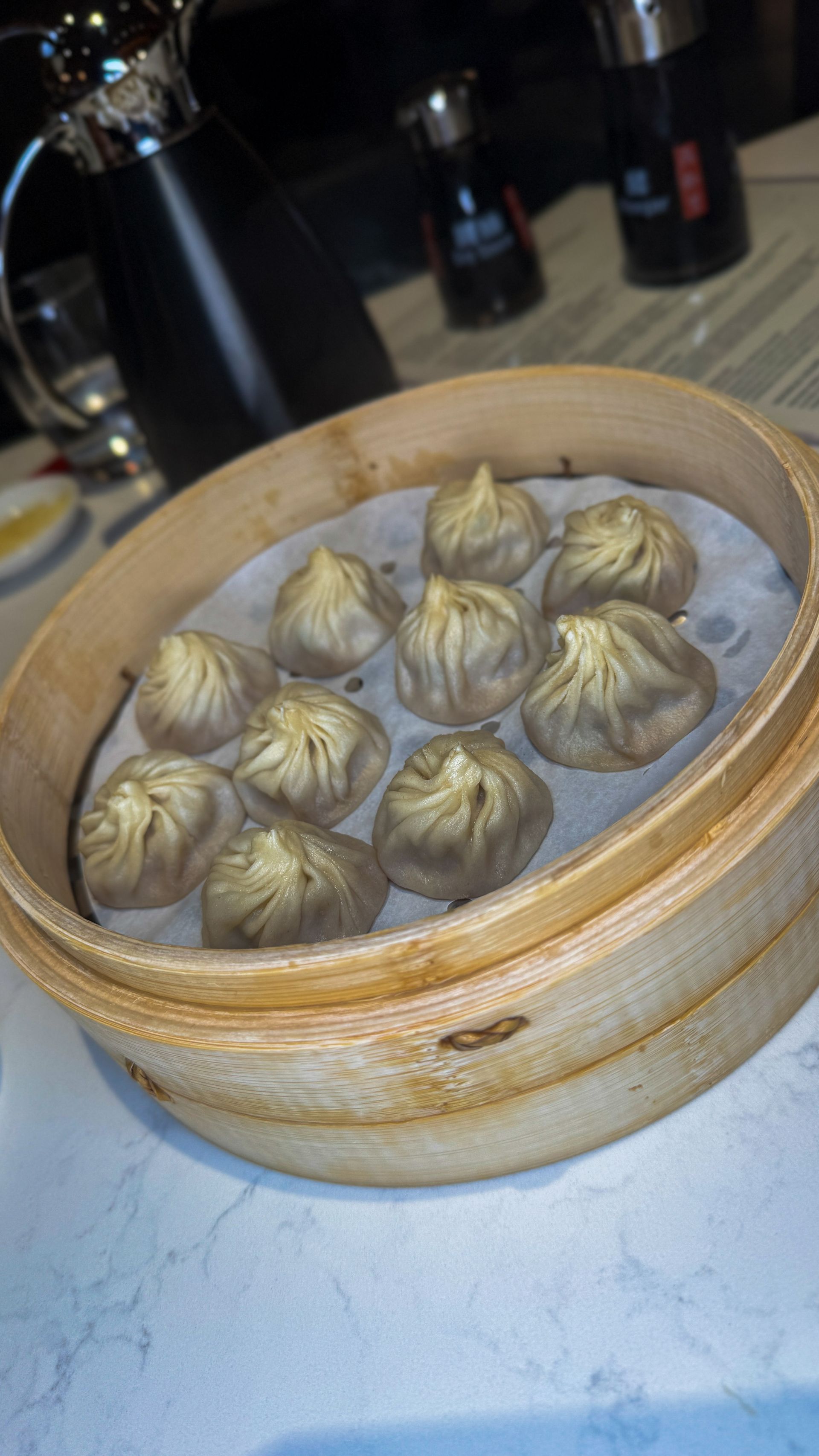 Bamboo steamer basket filled with steamed dumplings on a table