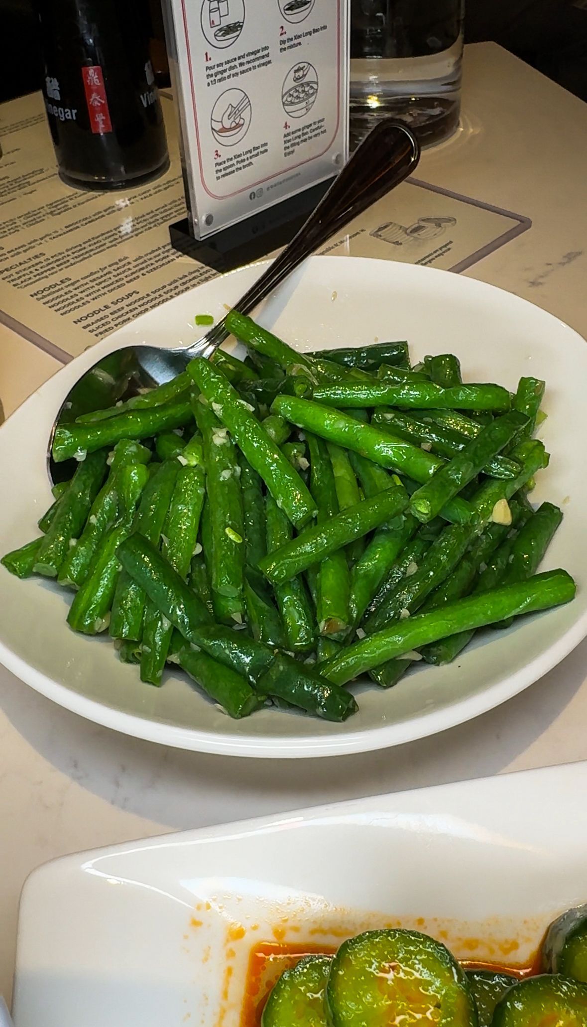Plate of glossy green stir-fried vegetables on a table in a restaurant setting