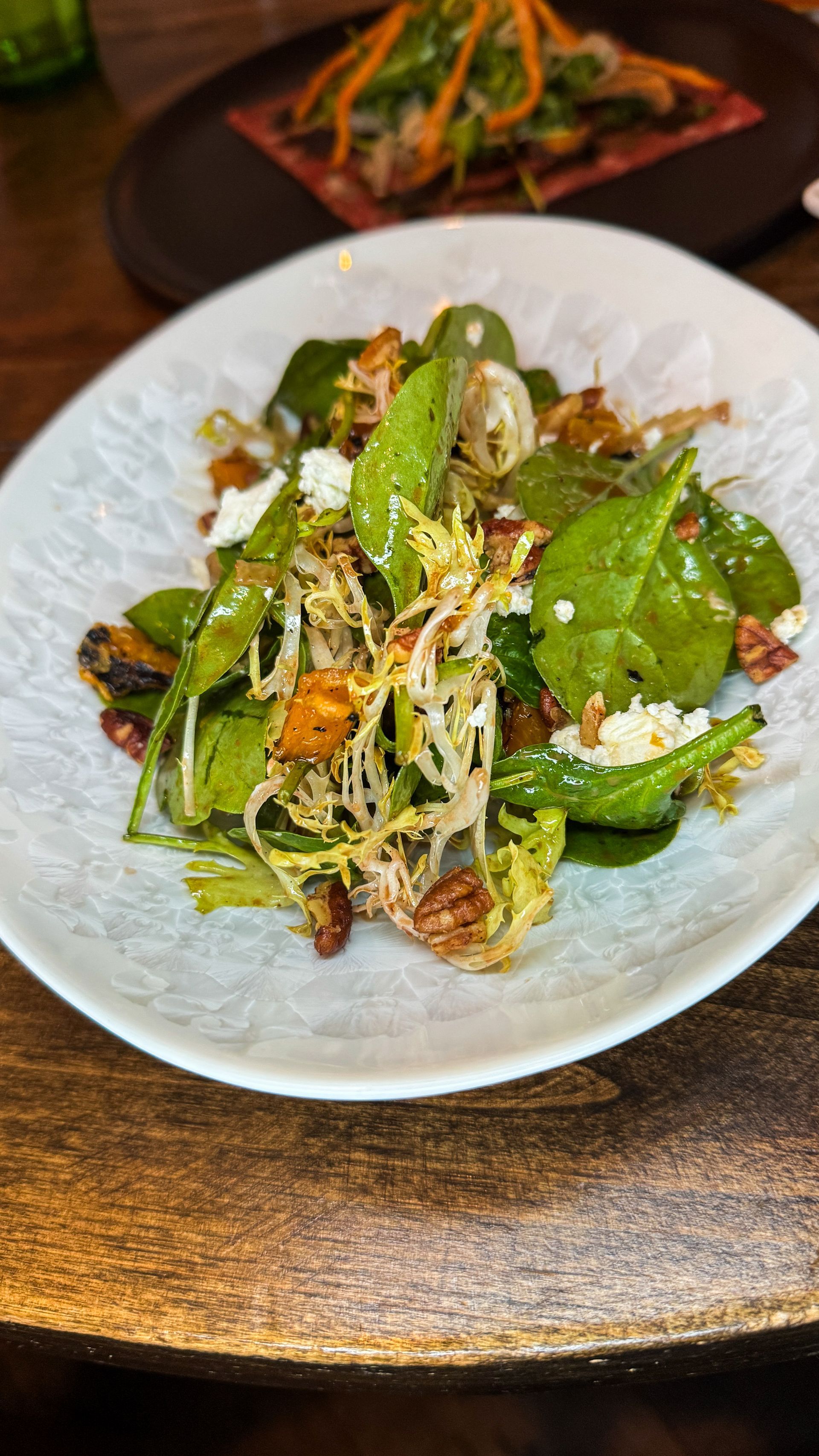 Green salad with lettuce, croutons, and shaved cheese on a white plate