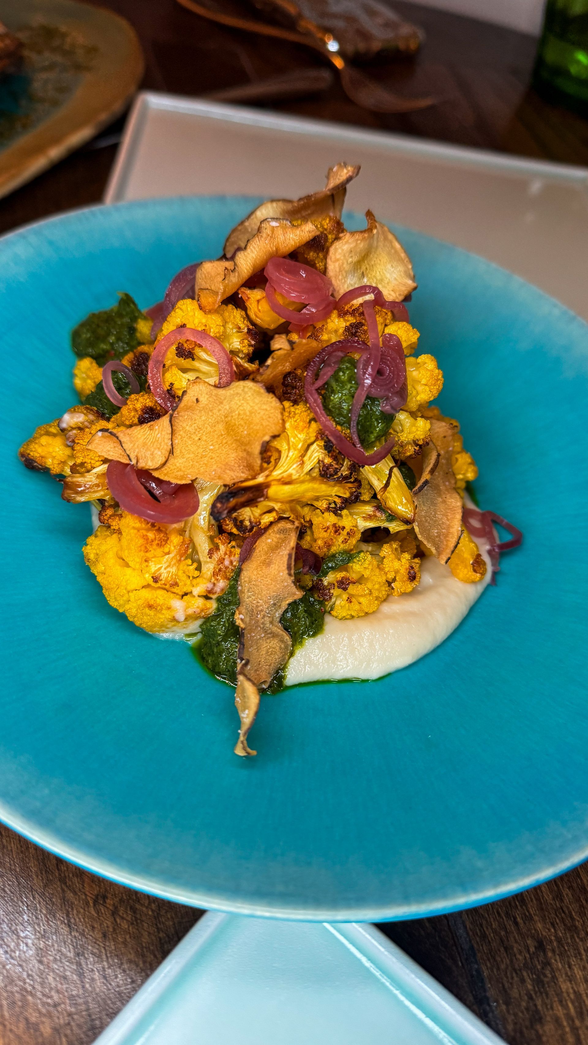 Blue plate with a colorful vegetable and herb-topped dish on a restaurant table
