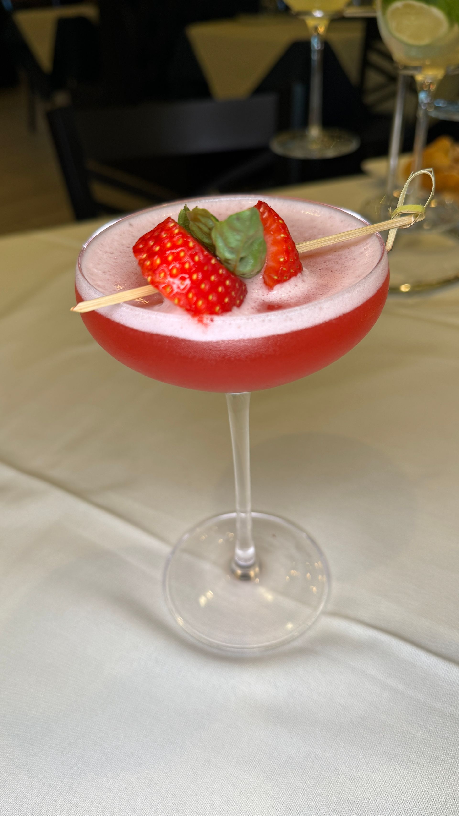 Strawberry cocktail in a coupe glass, garnished with strawberries and mint.