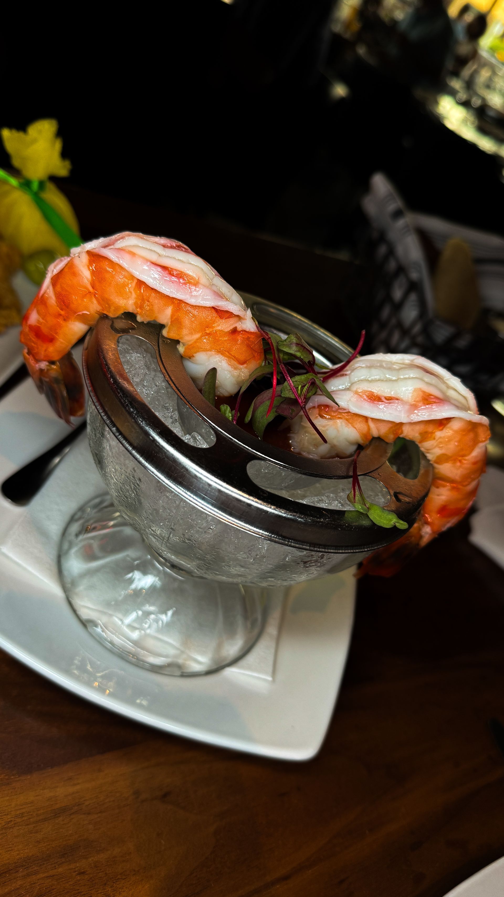 Lobster tail meat, displayed in a clear glass, resting on a white plate.