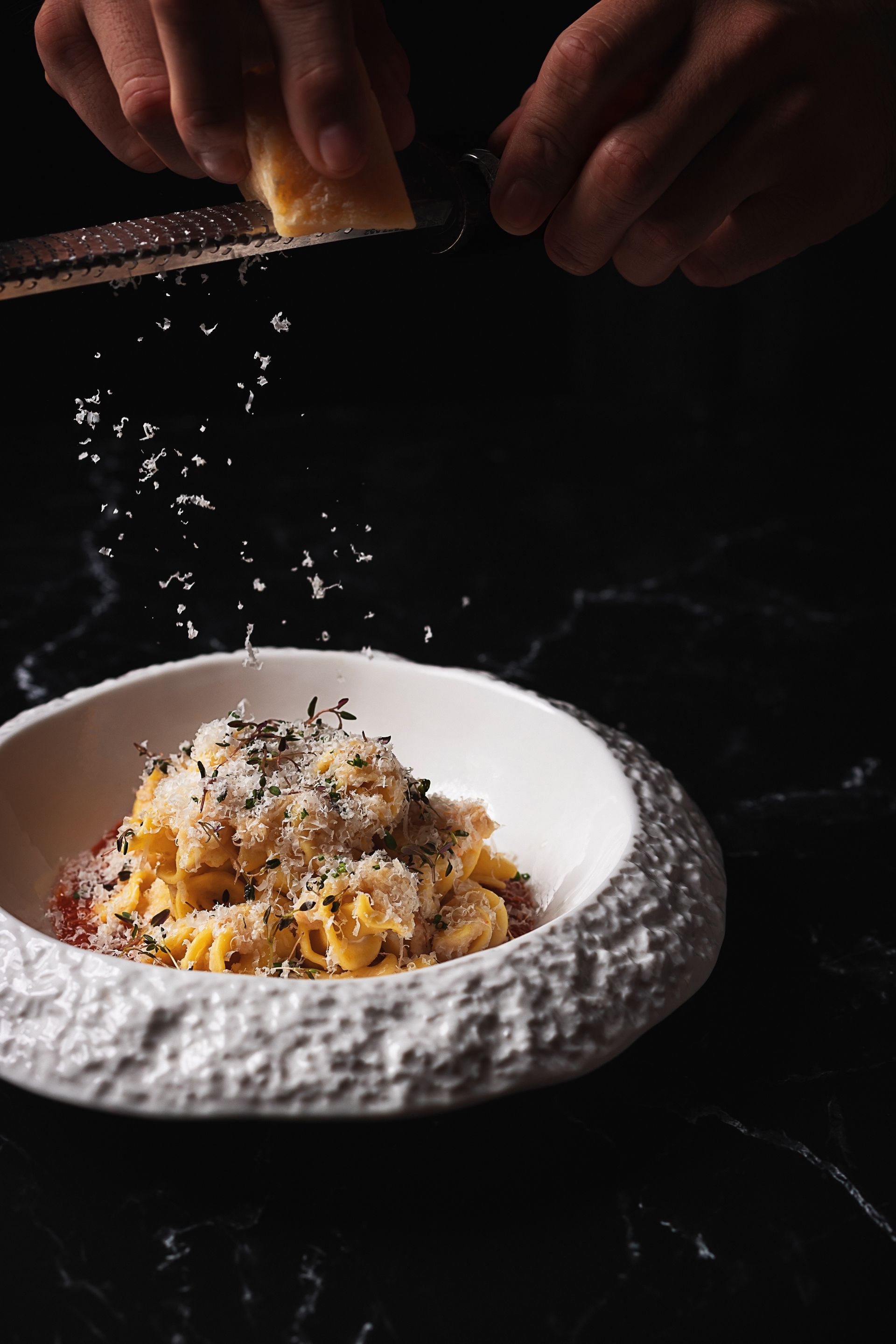 A person is grating cheese on a plate of food.