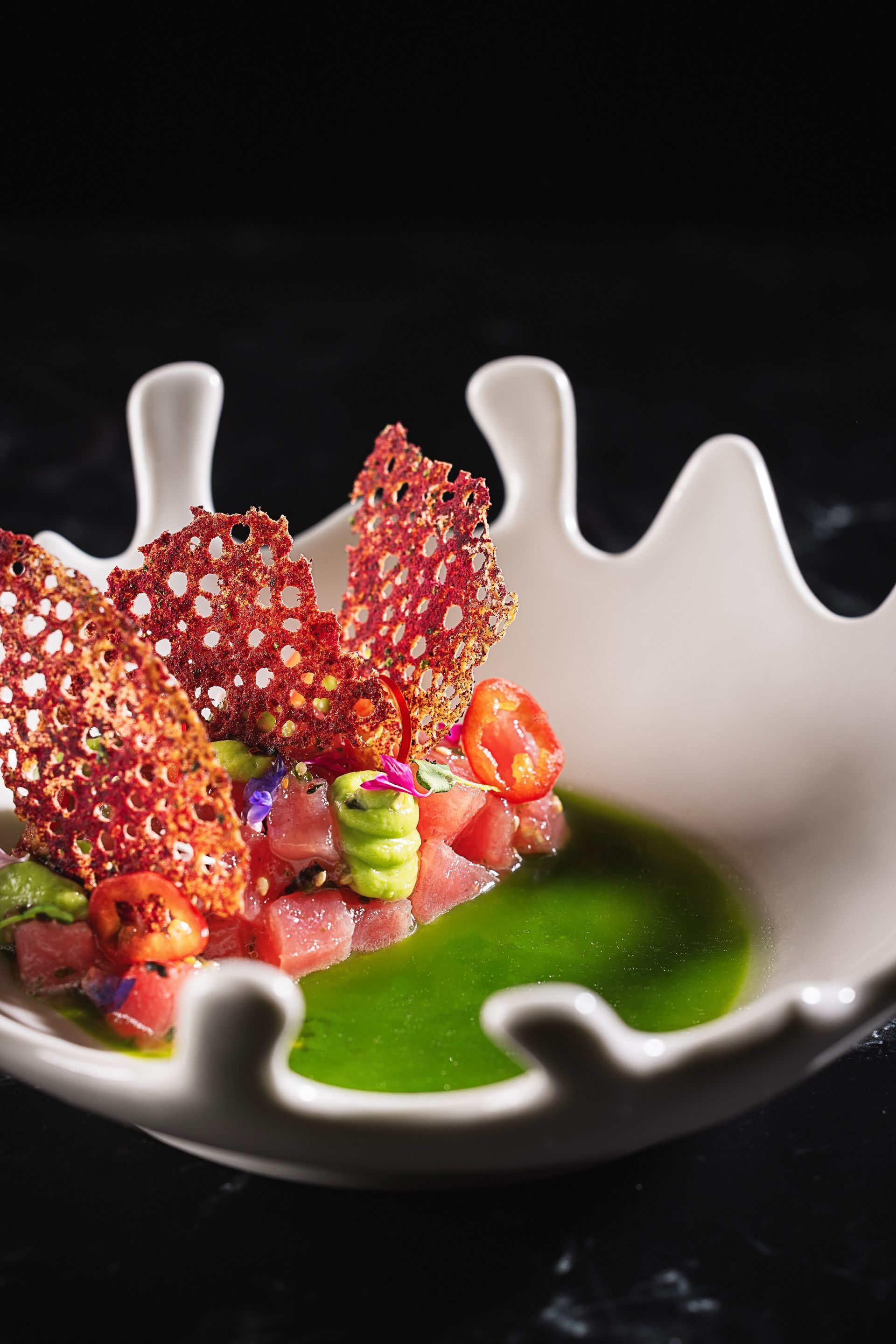 A white bowl filled with food and green sauce