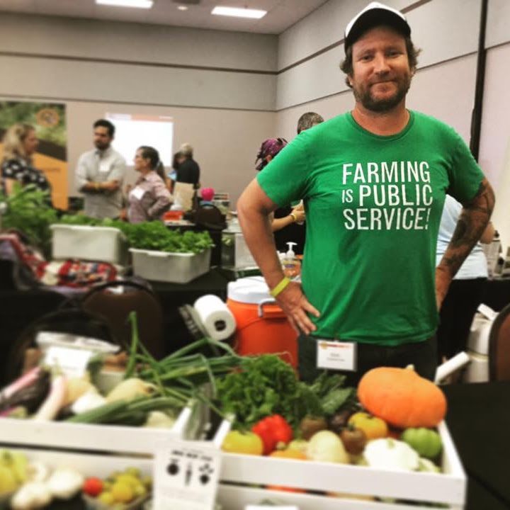 A man wearing a green shirt that says farming is public service