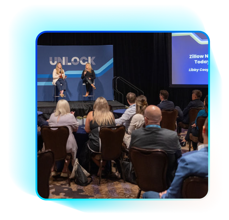 Two women on stage at a conference, facing an audience.