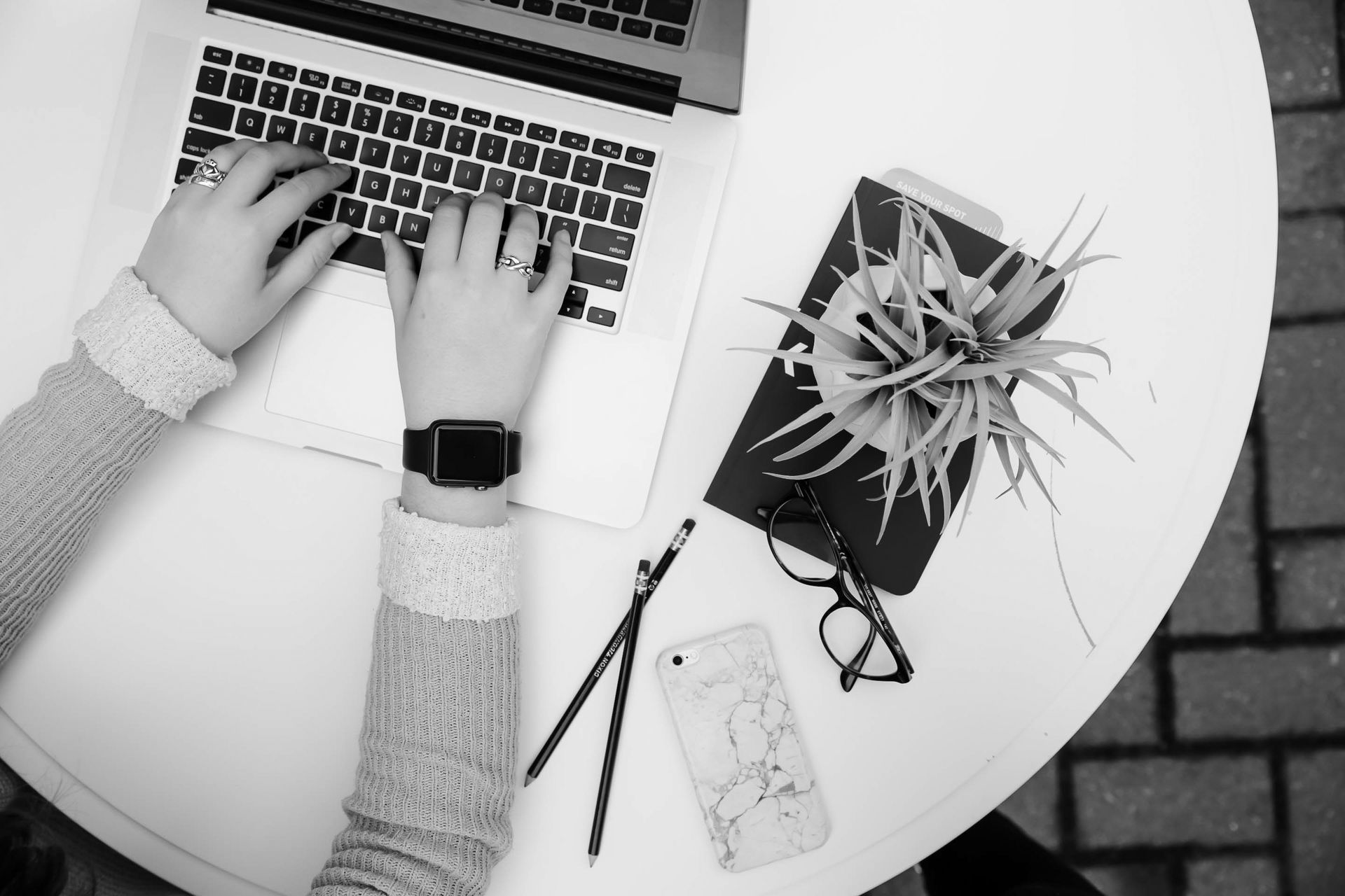 A person is typing on a laptop computer while wearing a watch.