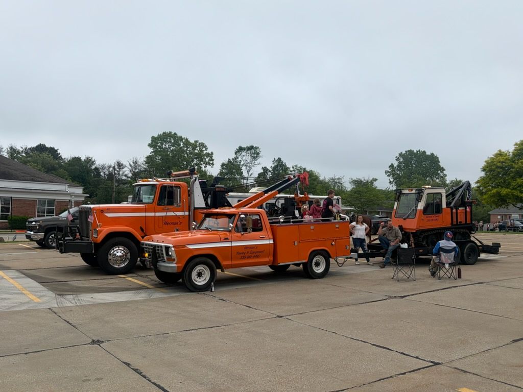 Orange tow trucks at a parking lot event with people gathered around them.