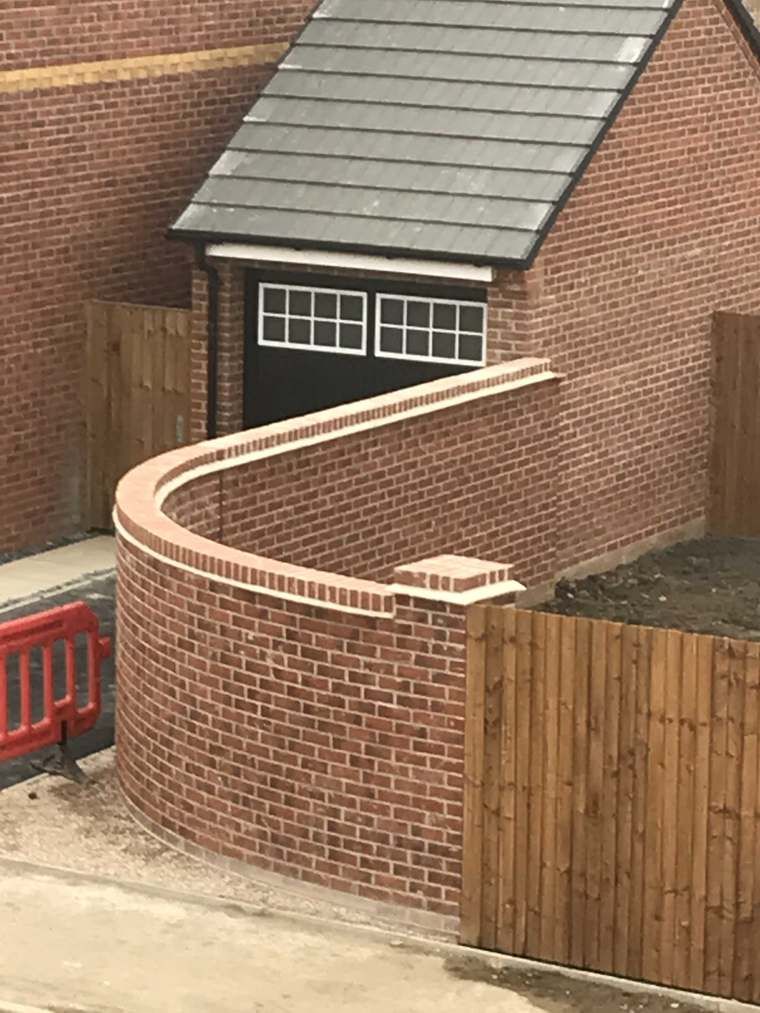 Close-up of a curved brick feature wall near a garage