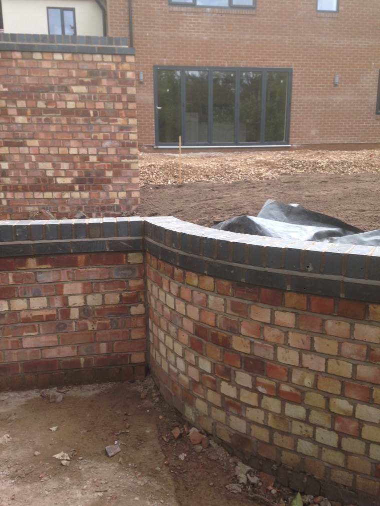 Curved brick boundary wall corner by a modern extension