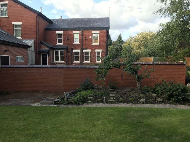 Finished red brick garden boundary wall with patio