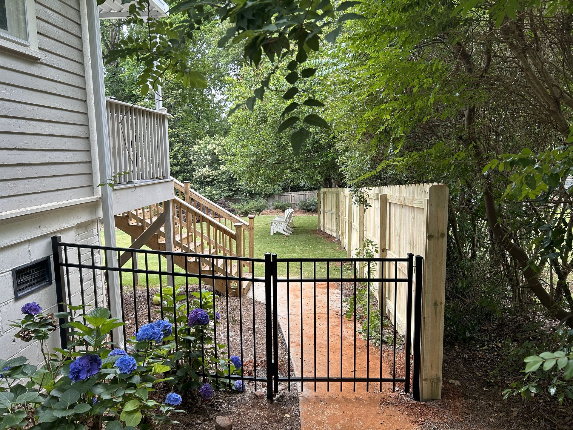A black fence surrounds a path leading to a house.
