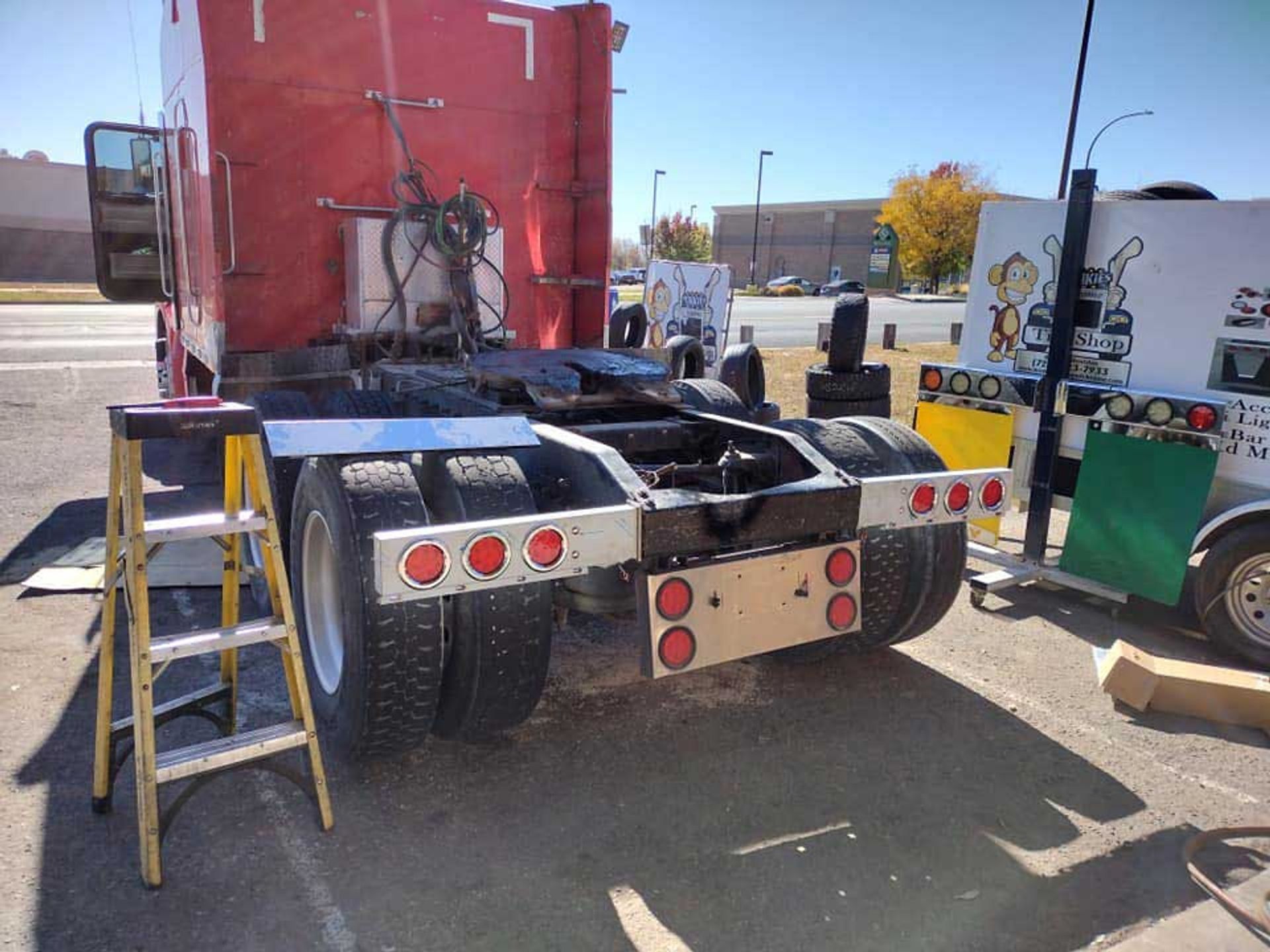 A red semi truck is parked next to a yellow ladder