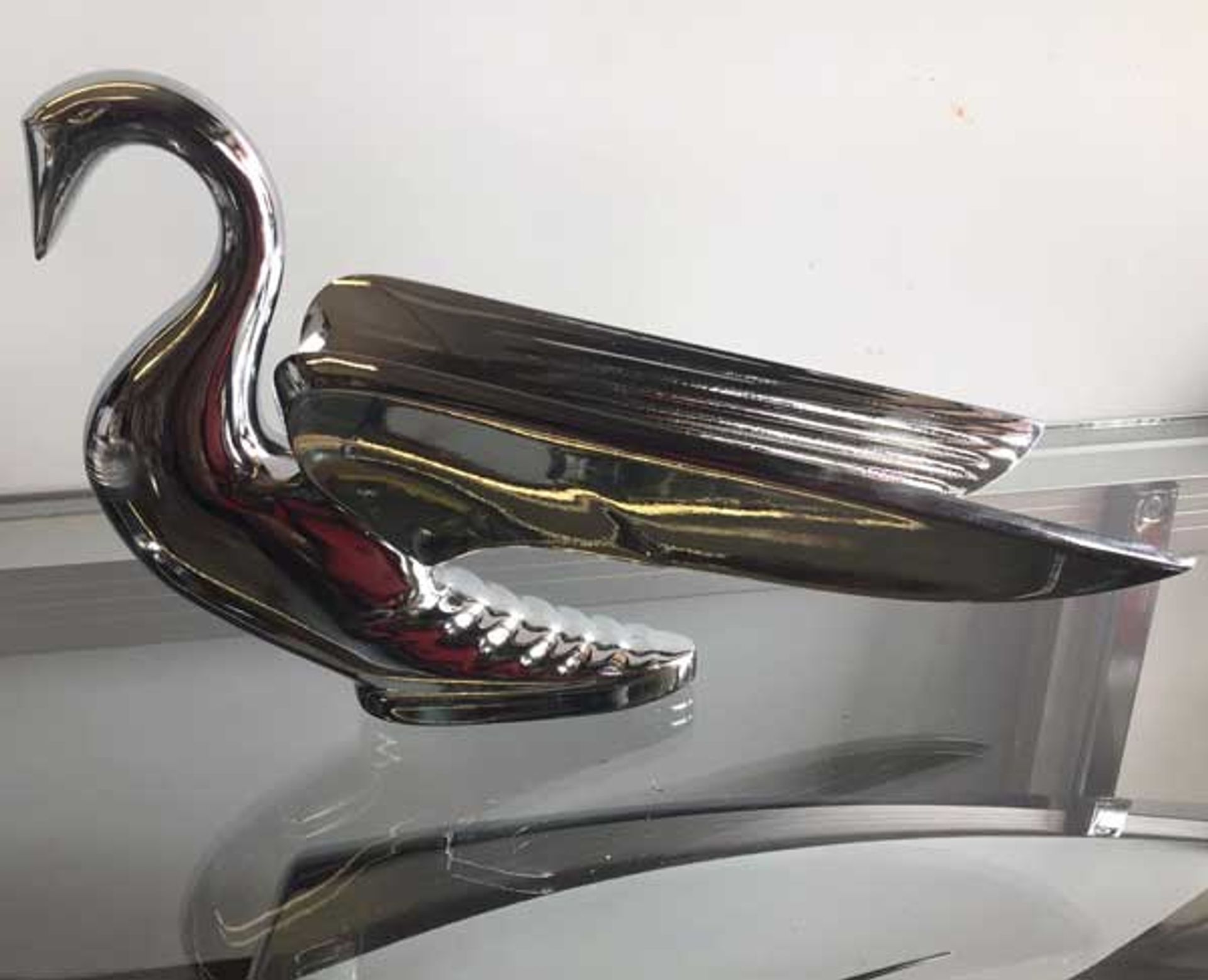 A silver swan is sitting on top of a glass table.
