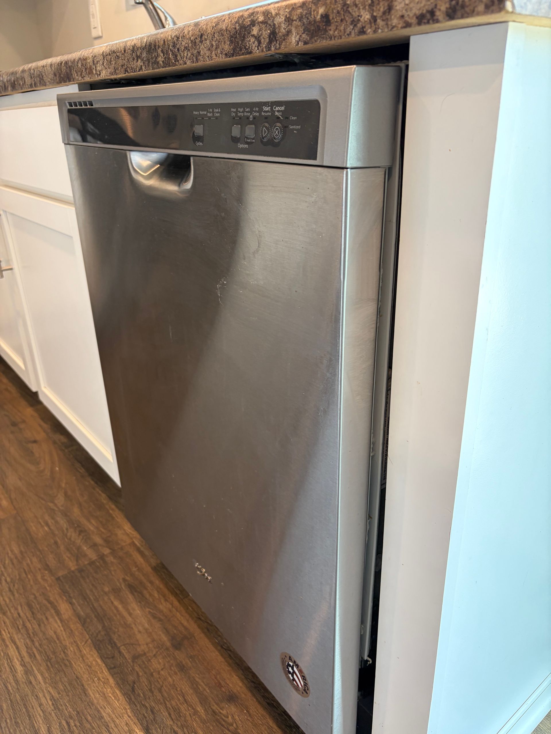 Stainless steel dishwasher built into a kitchen cabinet under a countertop.