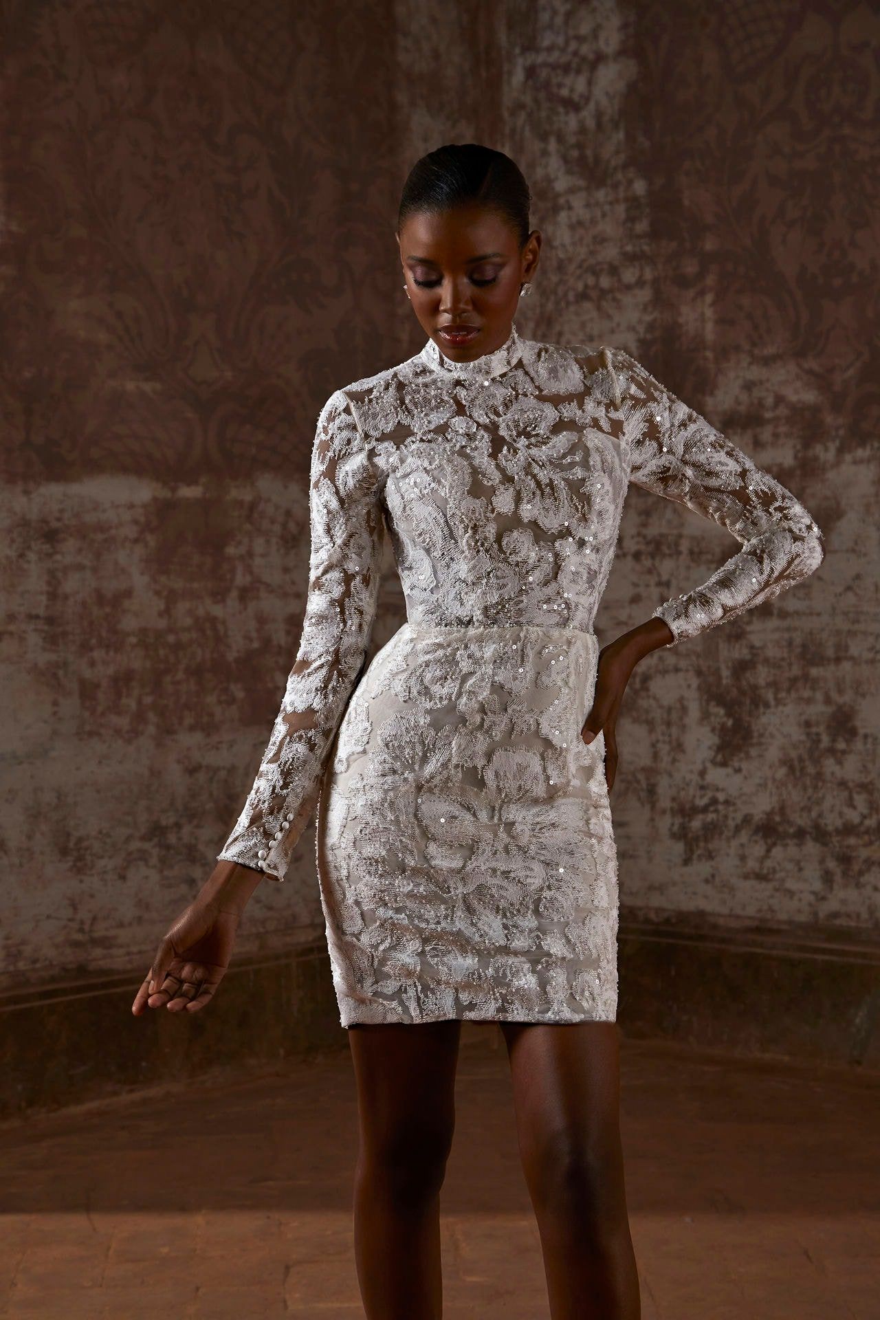 A woman is wearing a white lace dress with long sleeves.