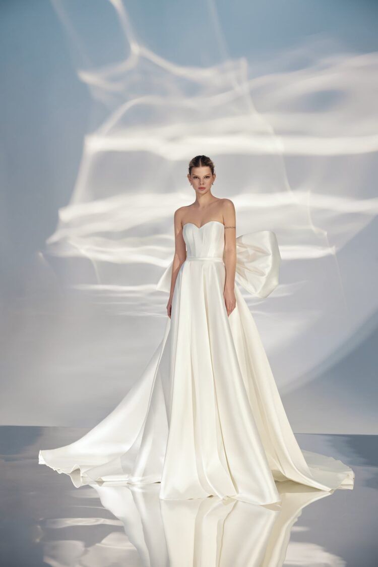 A woman in a white wedding dress is standing on a runway.