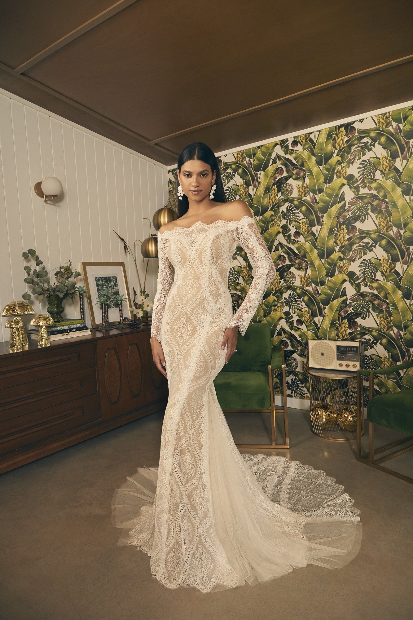 A woman in a white lace wedding dress is standing in a room.