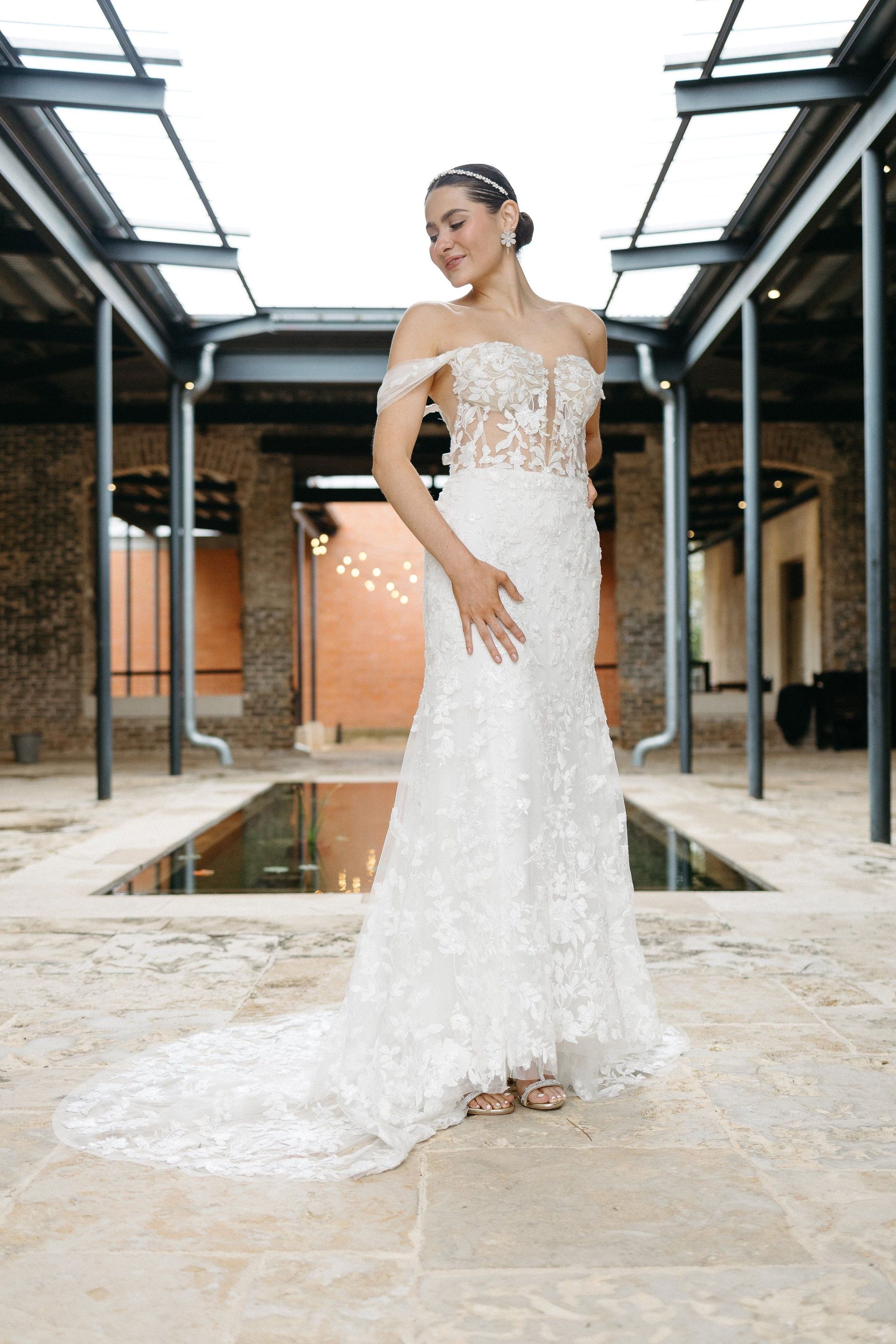 A bride in a wedding dress is sitting on the ground holding a bouquet of flowers.