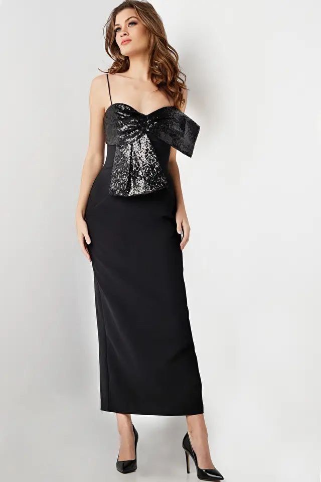 A woman is wearing a black dress with a bow on the top.