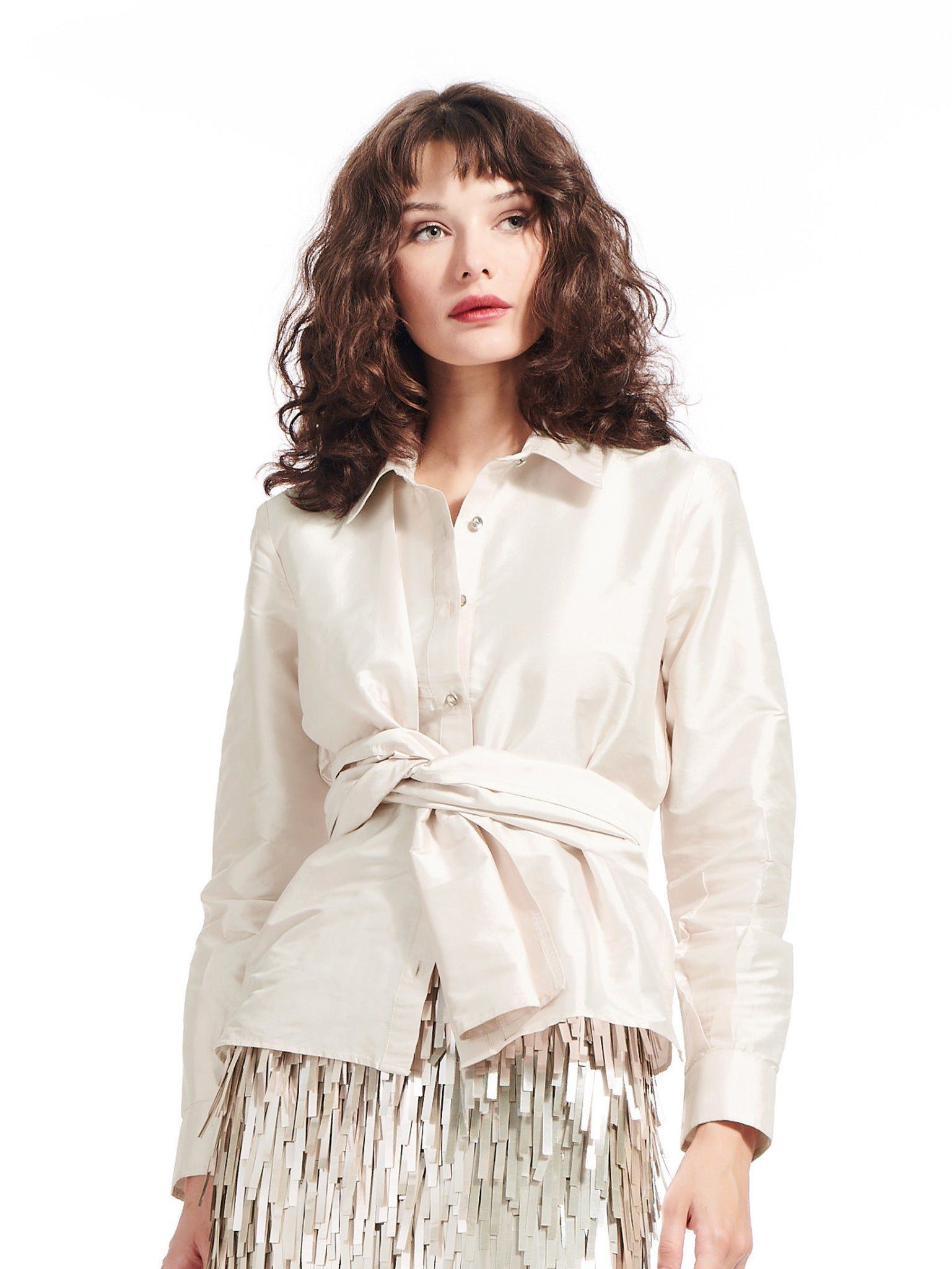 A woman is wearing a white shirt and a sequined skirt.