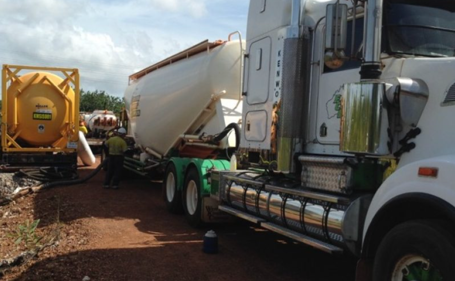 A Person Is Pouring Concrete Into A Container With A Shovel — Frontier Cement Supplies In East Arm, NT