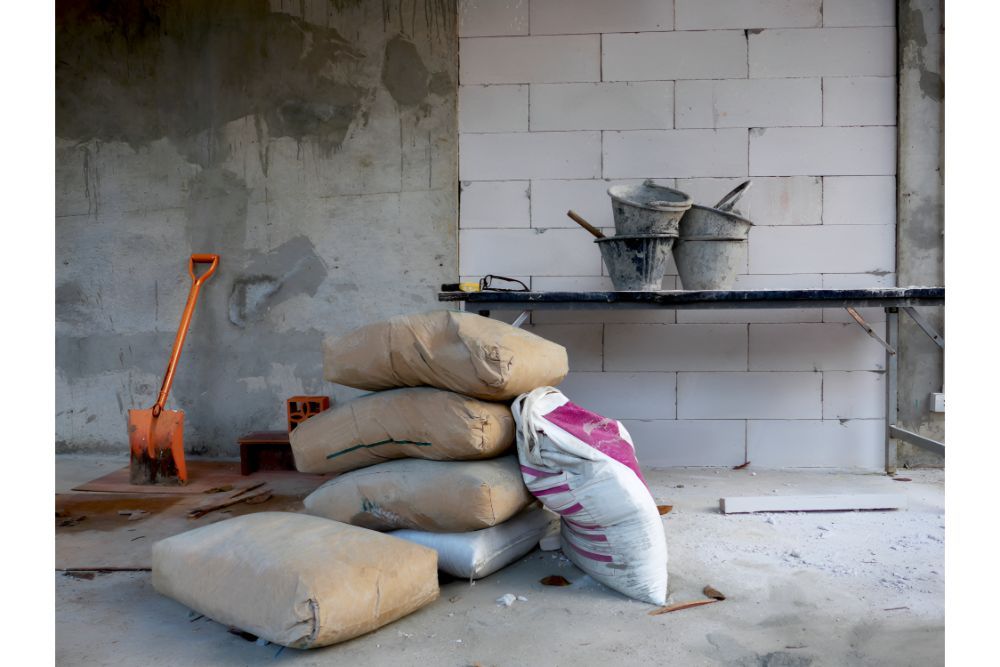 A Pile Of Bags Of Cement Are Stacked On Top Of Each Other In A Room — Frontier Cement Supplies In East Arm, NT