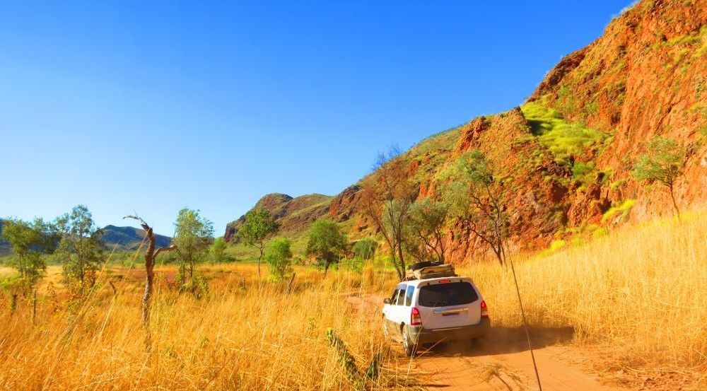 A White Suv Is Driving Down A Dirt Road In The Desert — Frontier Cement Supplies In Kununurra, NT