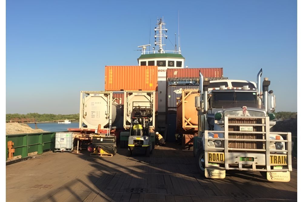 Two Trucks Are Parked In Front Of A Boat With Containers On It — Frontier Cement Supplies In East Arm, NT
