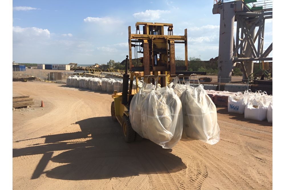 A Forklift Is Carrying A Bunch Of Bags On A Dirt Road — Frontier Cement Supplies In Geraldton, NT