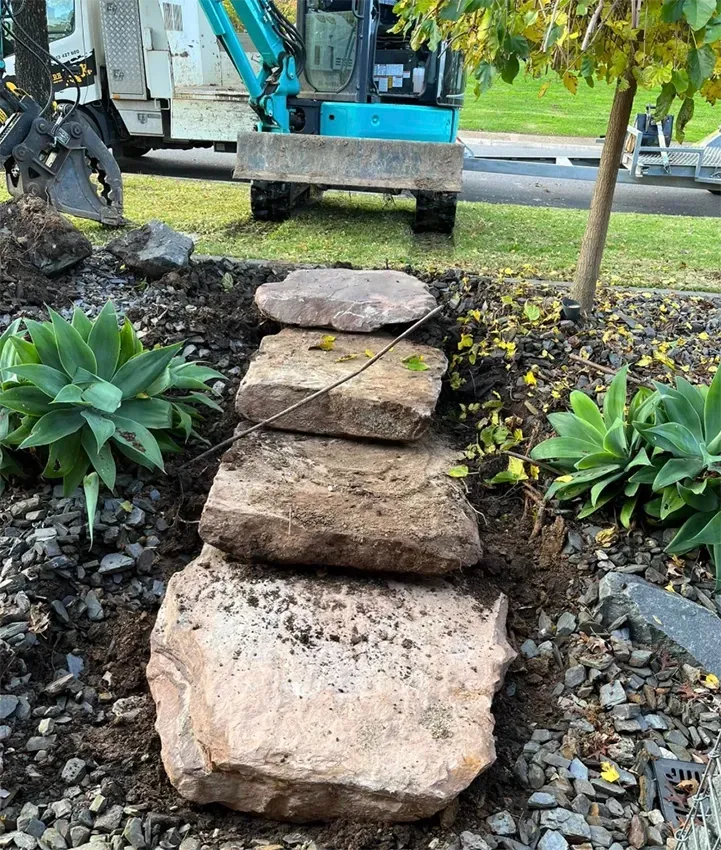 An Excavator Laying a Bush Rock Path in a Garden— Robbo's Hire In Wodonga, VIC