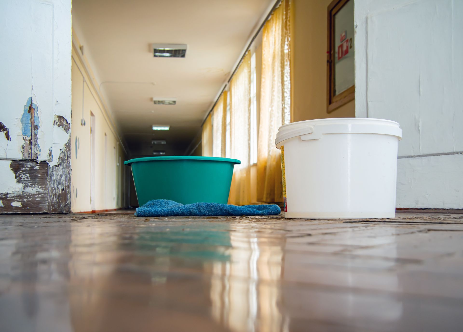 Water damage restoration with buckets collecting leaks on the flooded hallway floor. Water damage restoration with buckets collecting leaks on the flooded hallway floor.