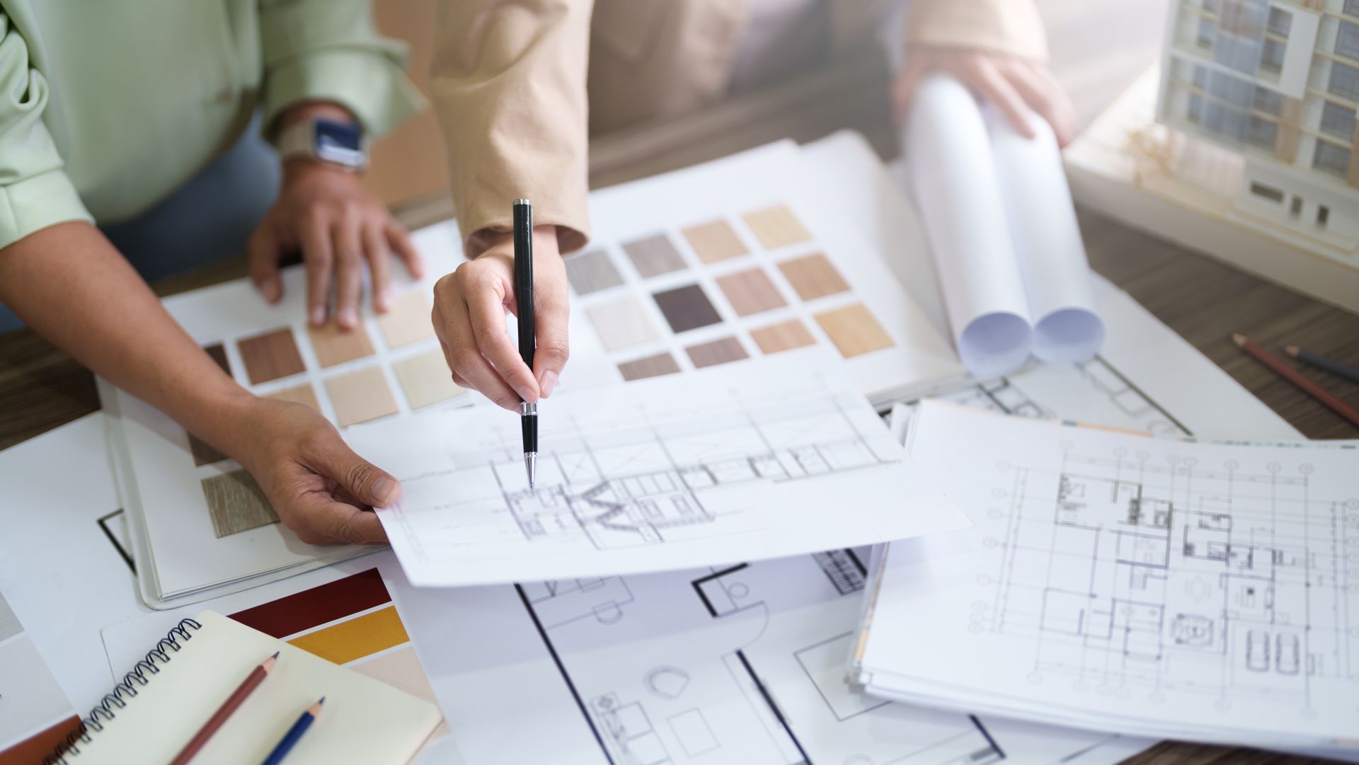 People reviewing architectural floor plans and color swatches on a desk