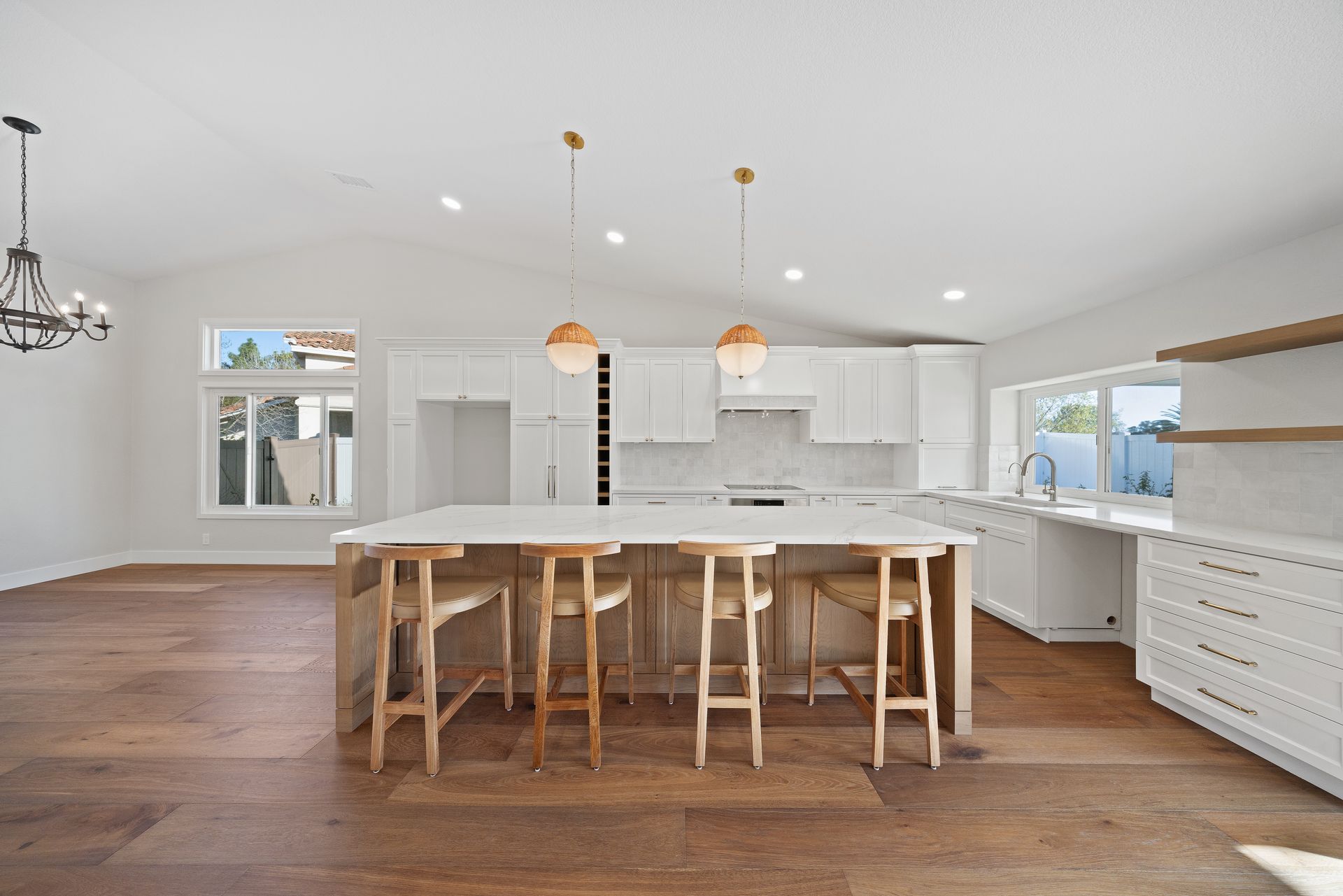 Modern white kitchen with wood island, bar stools, pendant lights, and hardwood floors