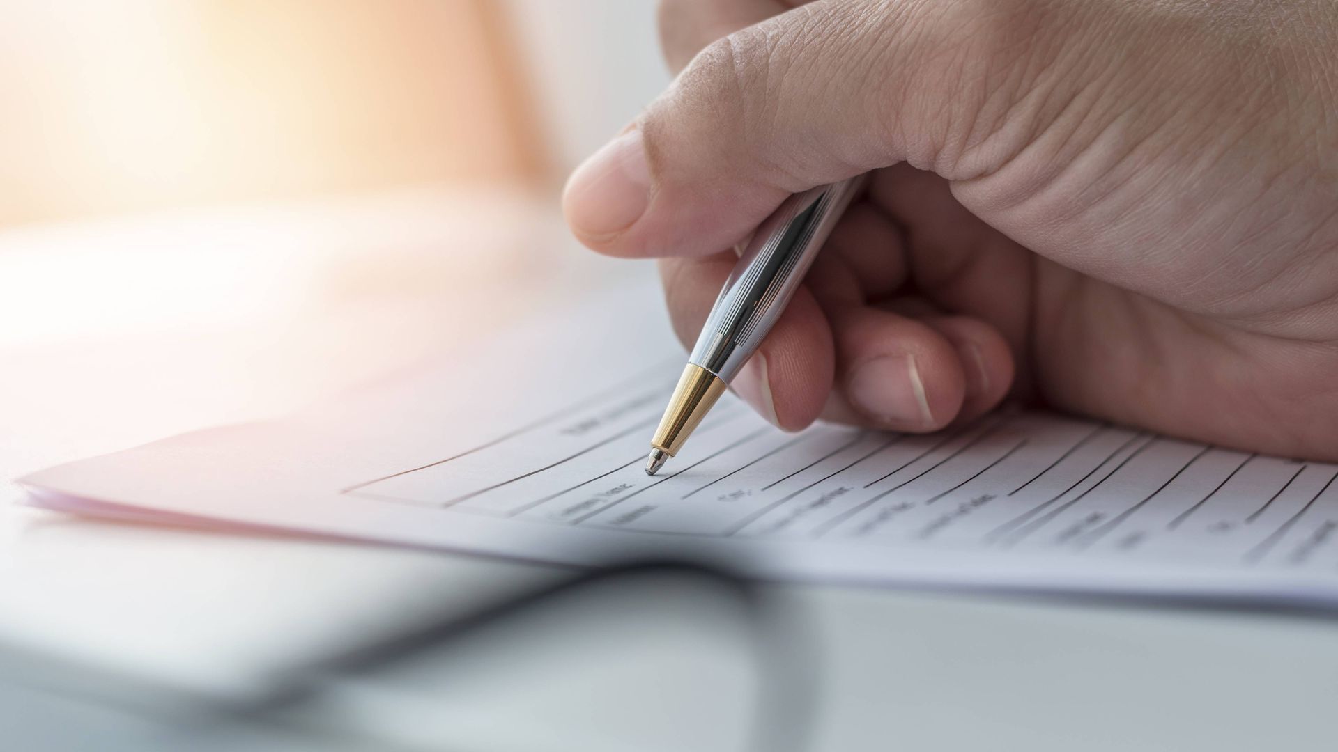 A person is writing on a piece of paper with a pen.