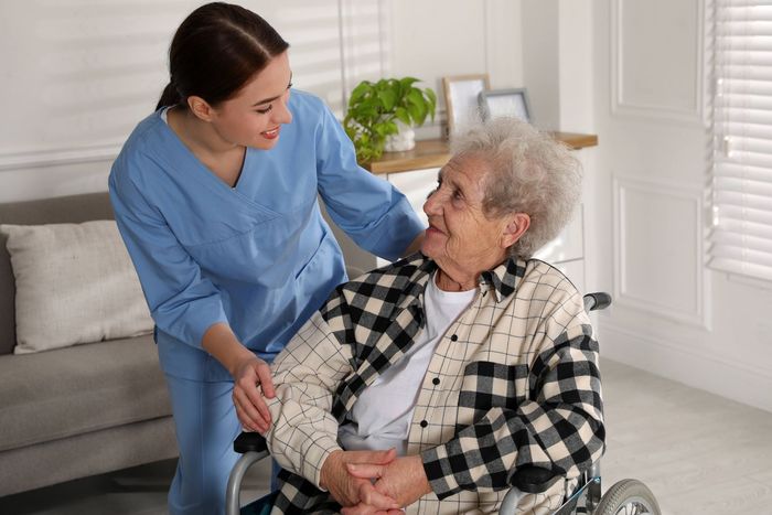 A nurse is helping an elderly woman in a wheelchair.
