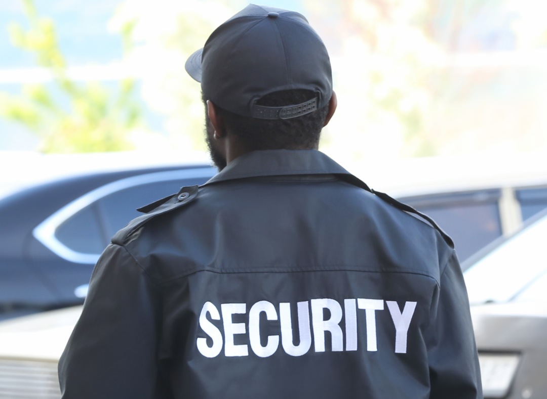A security guard is standing in front of a parking lot.