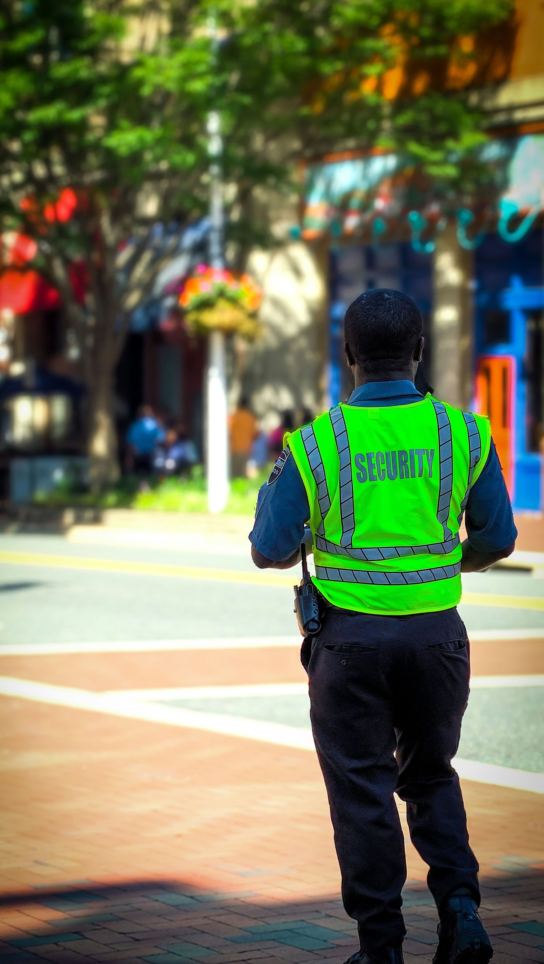 A man in a green vest is walking down a street.