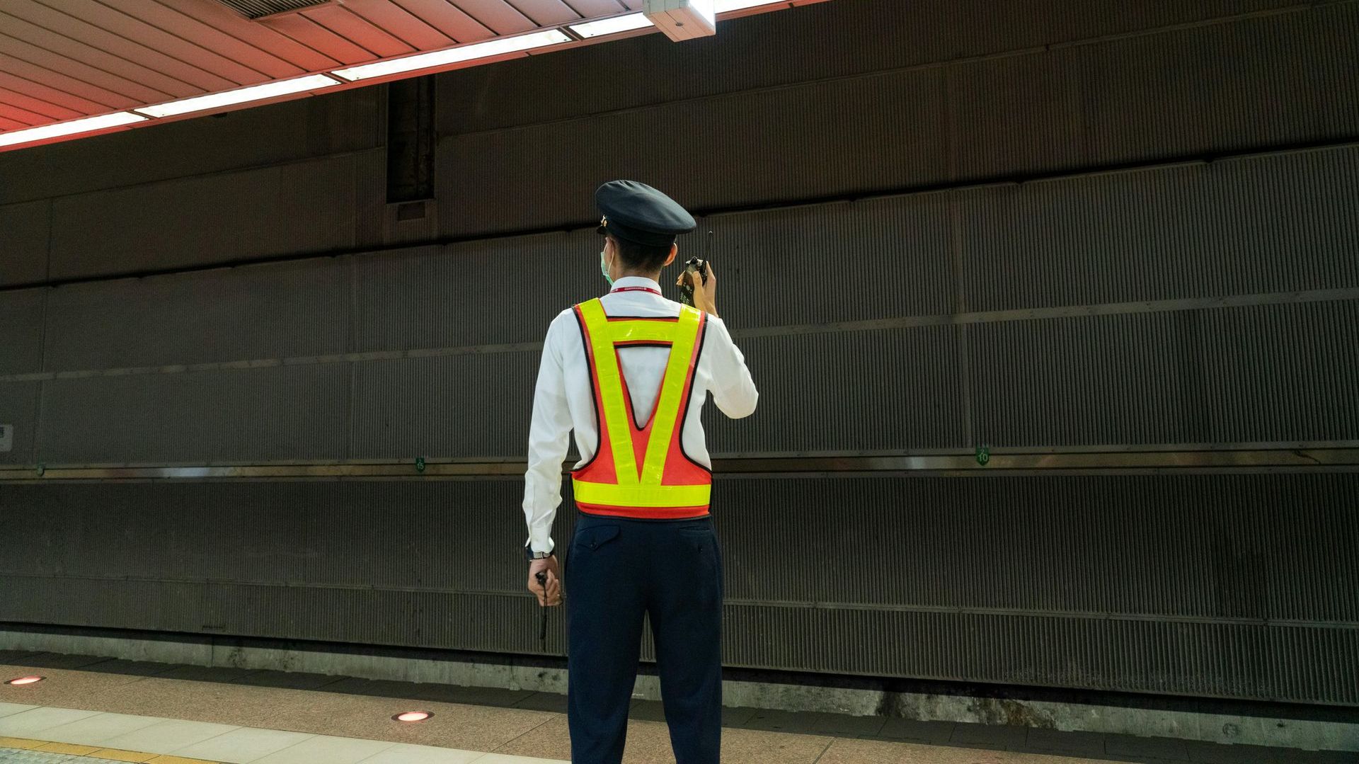 A man in a safety vest is standing in front of a wall.