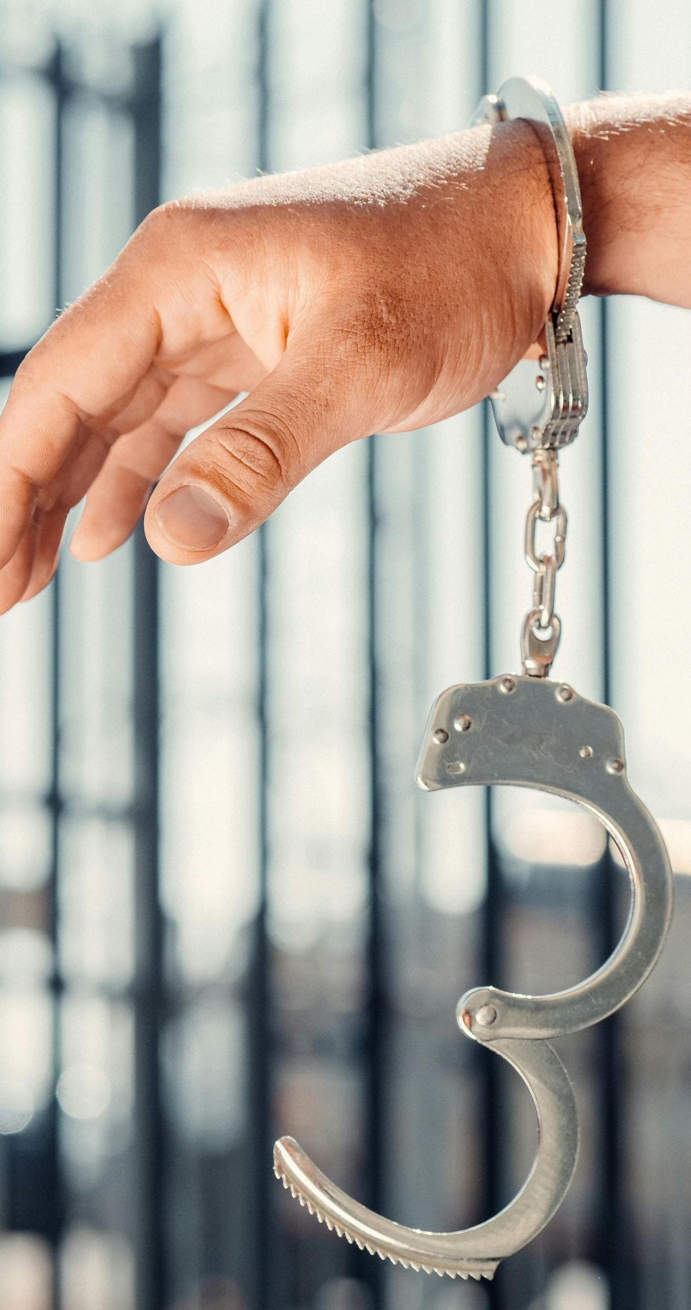 A person is holding a pair of handcuffs on their wrist.