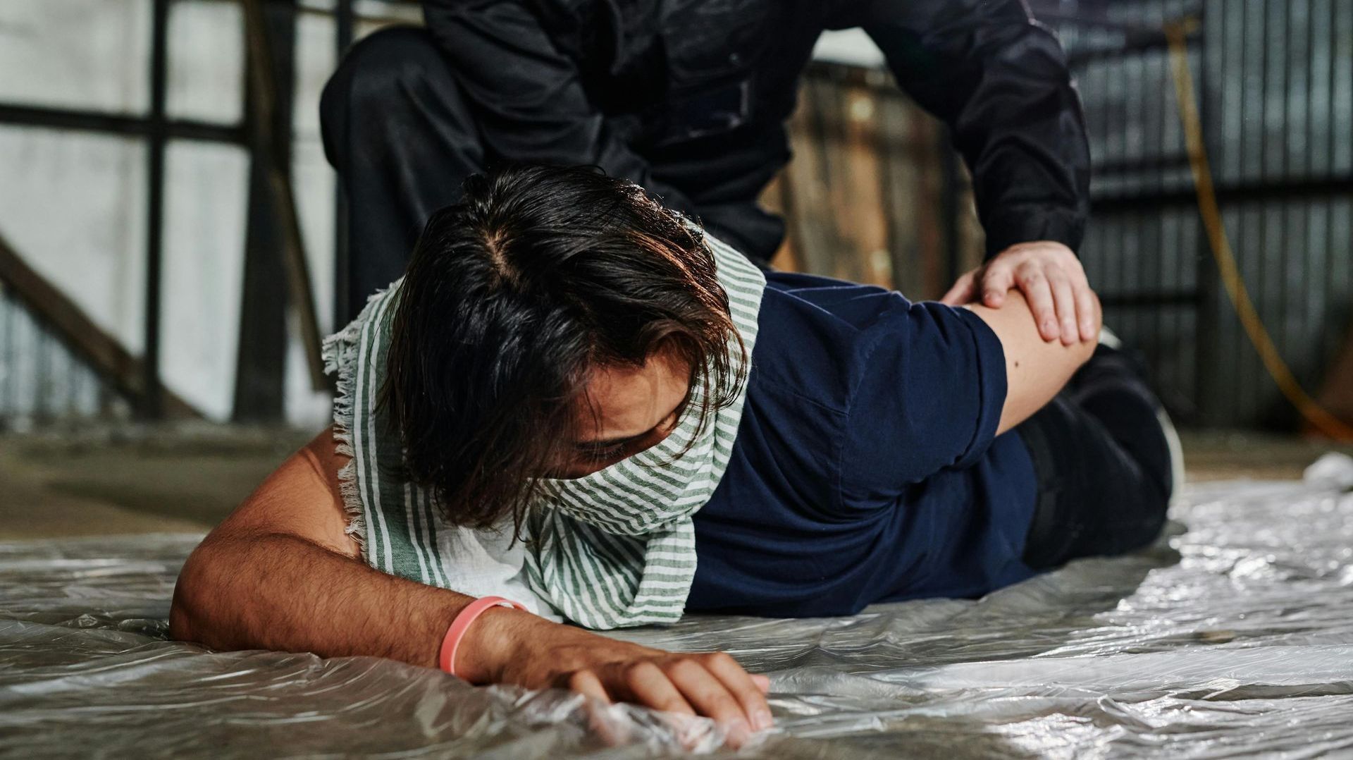 A man is laying on the floor with a bandana around his face.