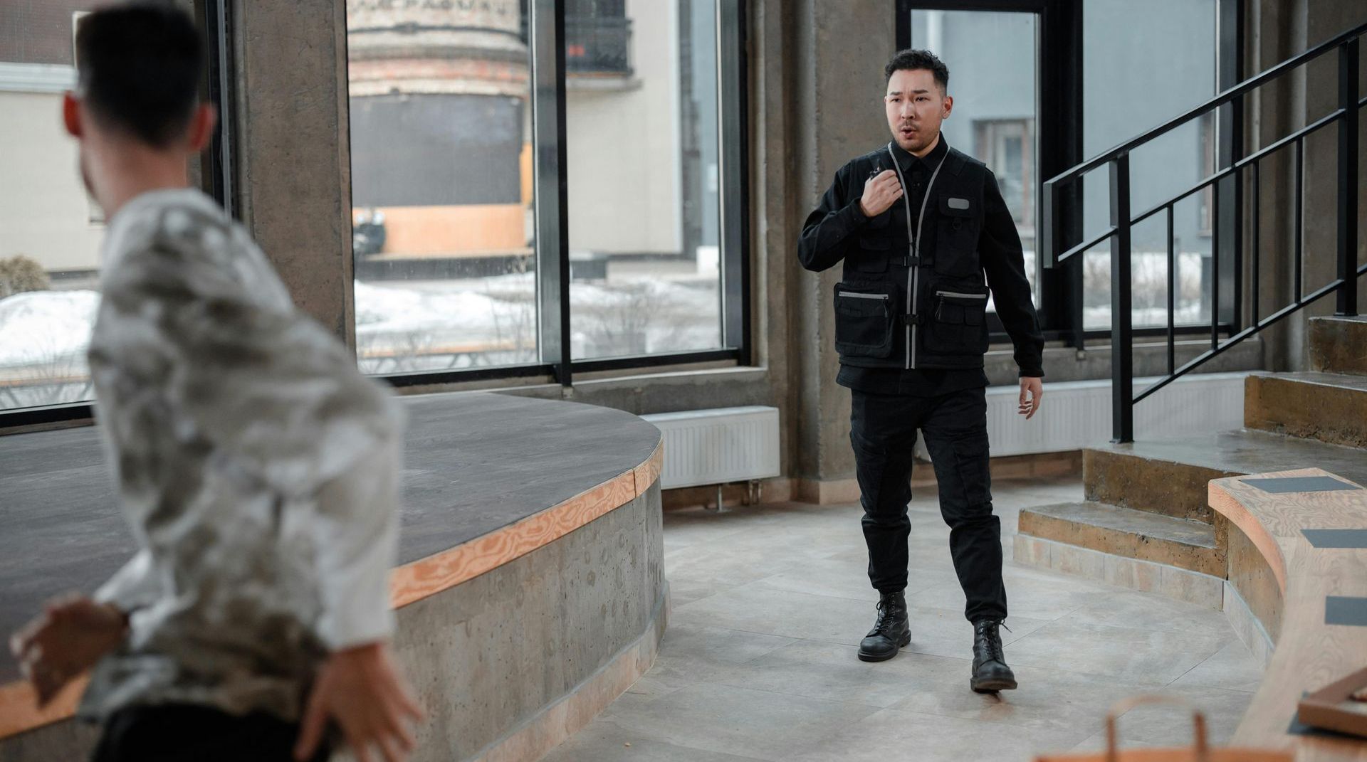 A man in a black jacket is standing next to a man in a white shirt.