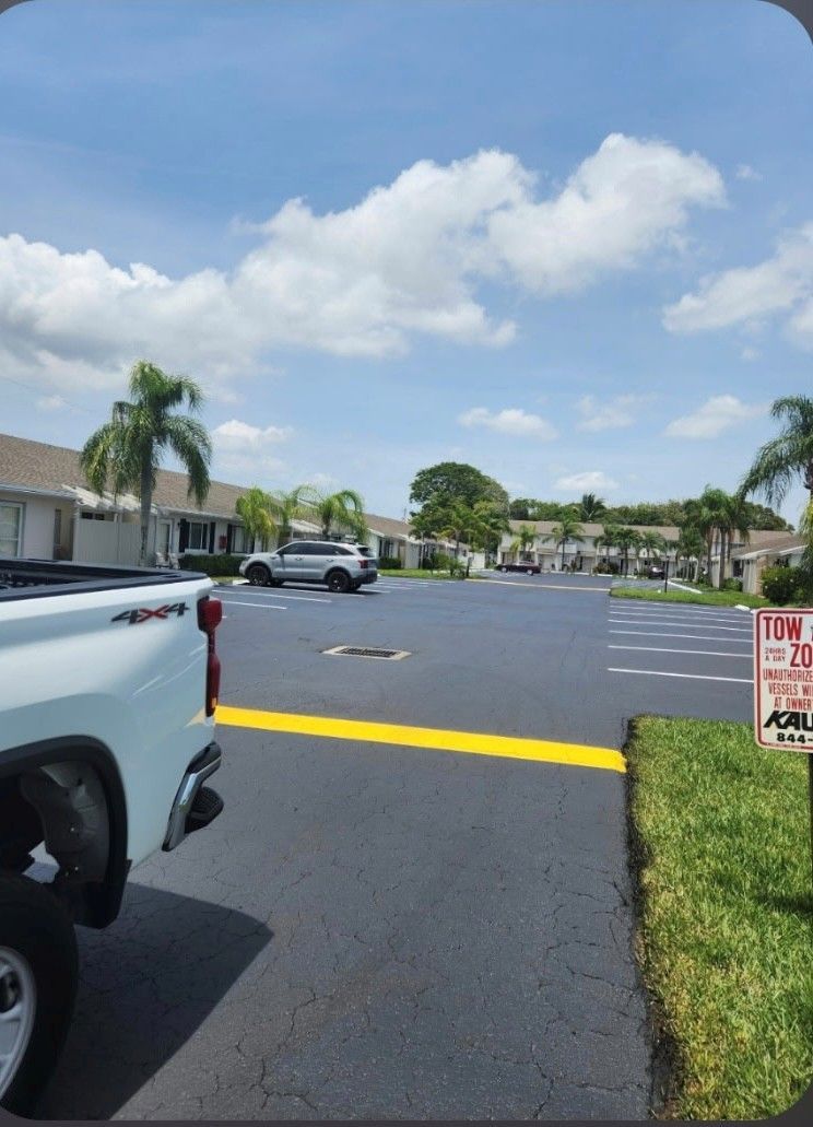 Parking lot with cars, palm trees, and a yellow curb under a partly cloudy sky