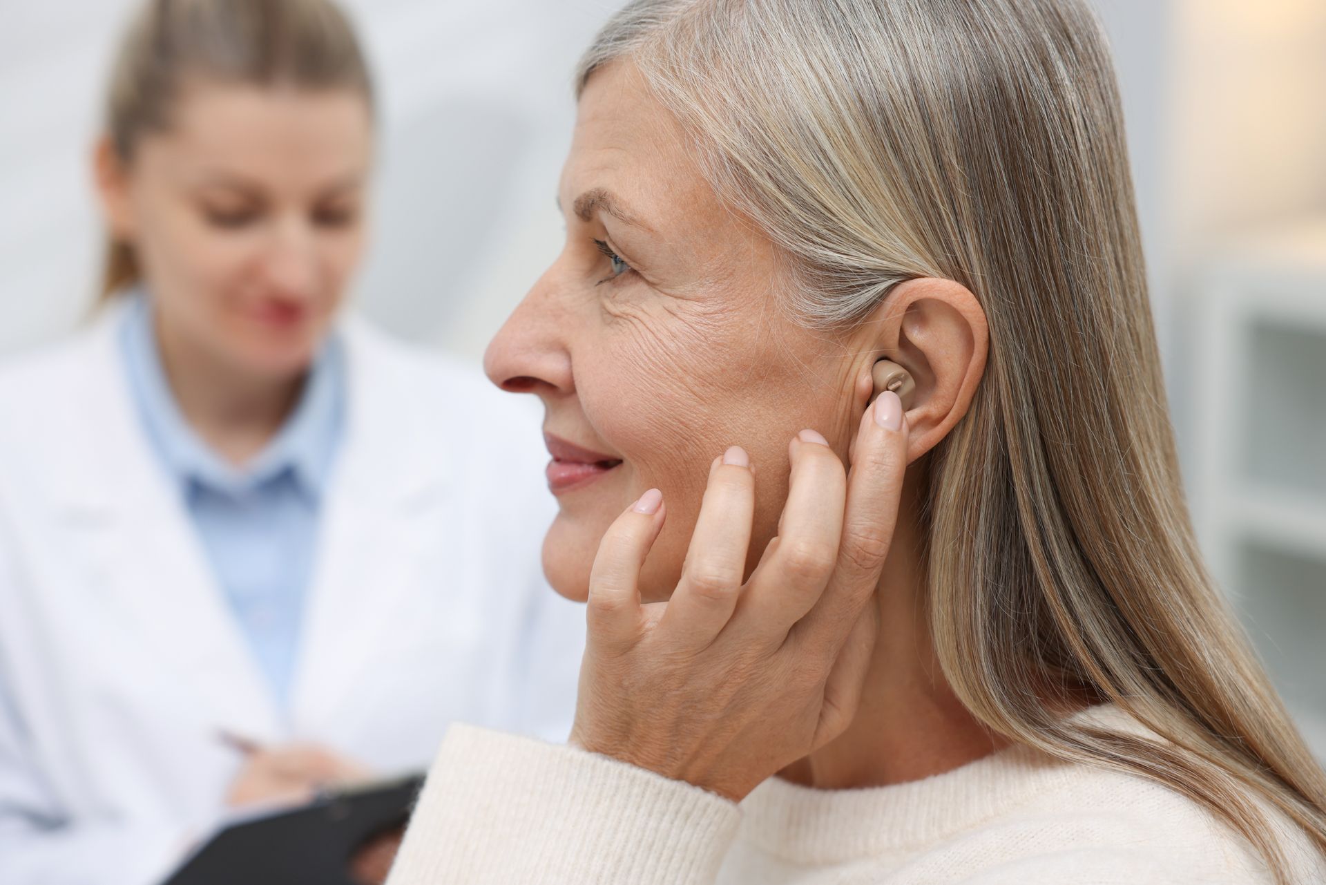 Senior woman wearing a hearing aid at a doctor's appointment in a clinic. Senior woman wearing a hearing aid at a doctor's appointment in a clinic.