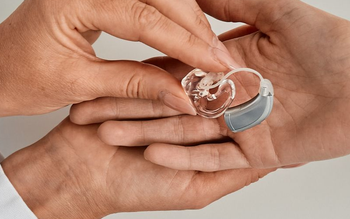 Audiometrist/ Audiologist passing hearing aid to a client informing of decisions. 