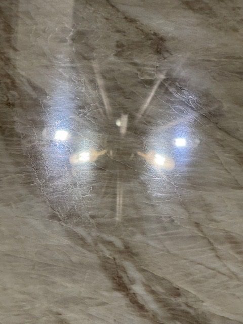 Close-up of a reflective metallic surface with bright light reflections and a marbled gray background