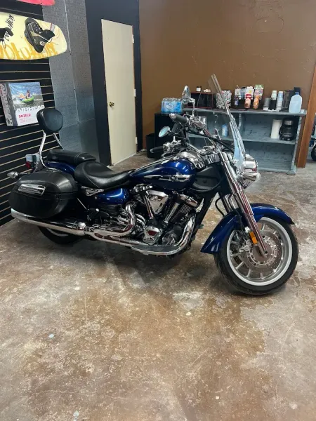 Blue touring motorcycle parked indoors beside a shelf and doorway